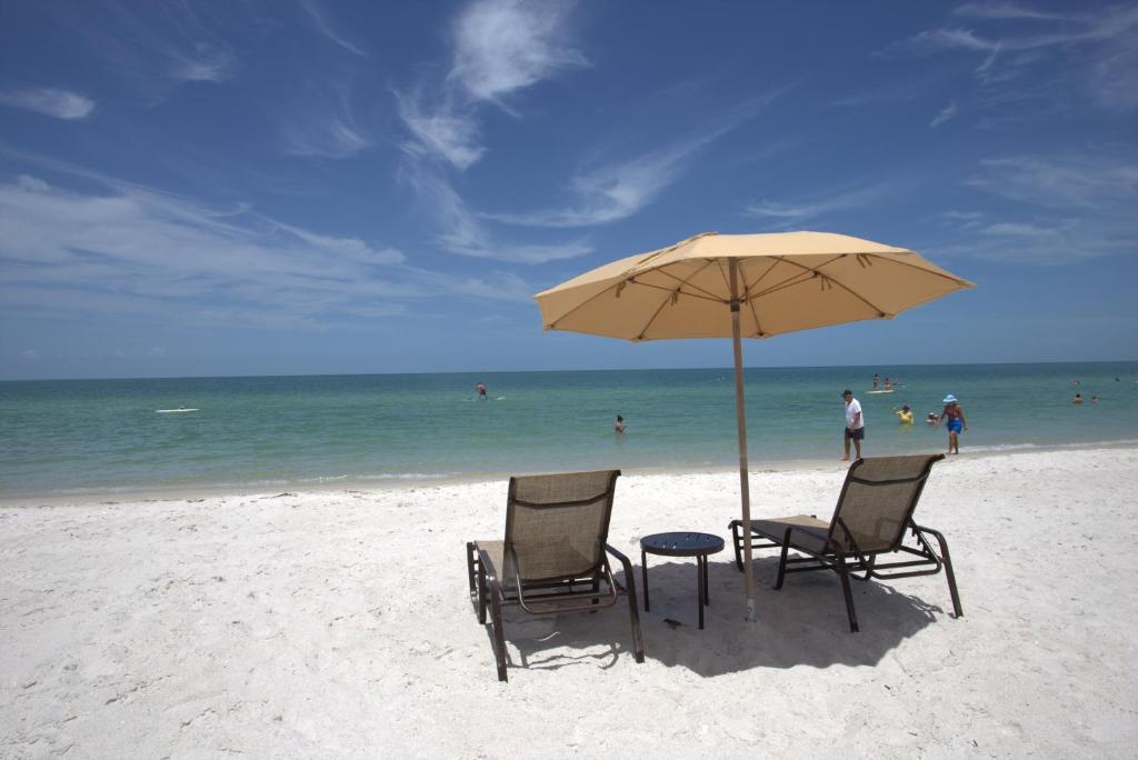 two chairs and a table under an umbrella on the beach at Vanderbilt Beach Resort in Naples