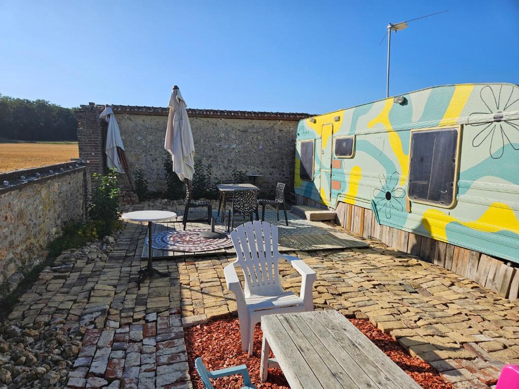 an rv with a table and chairs and an umbrella at Caravane look Dolce Vita climatisée in Gaudreville-la-Rivière