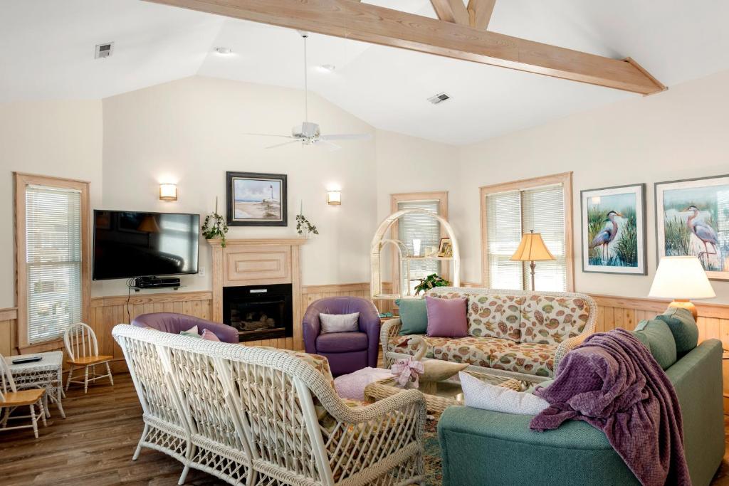 a living room with a couch and chairs and a tv at Fergusons Flagship in Nags Head