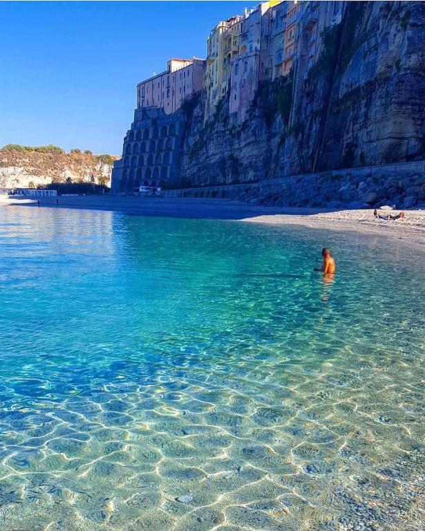 a man sitting in the water on a beach at Residenza Rivellini Tropea in Tropea