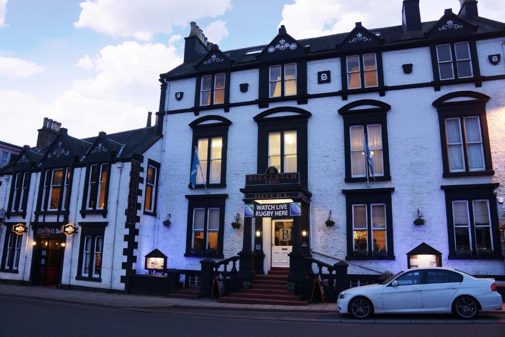 um carro branco estacionado em frente a um edifício azul em Buccleuch Arms Hotel em Moffat