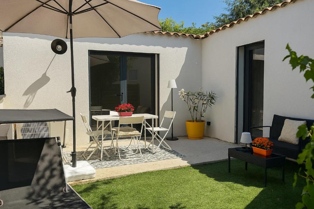 un patio avec un parasol, une table et des chaises dans l'établissement Maison moderne jardin piscine et parking prives, près d'Aix Centre, à Venelles
