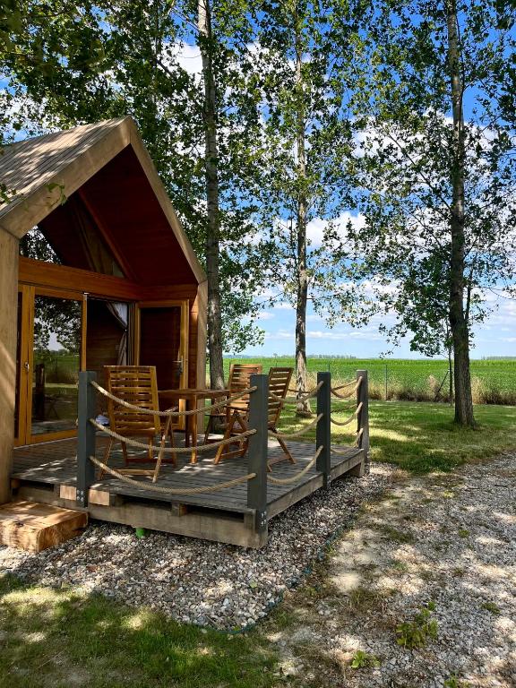 a cabin with chairs on a porch with a fence at Ritopia Glamping in Kovilj