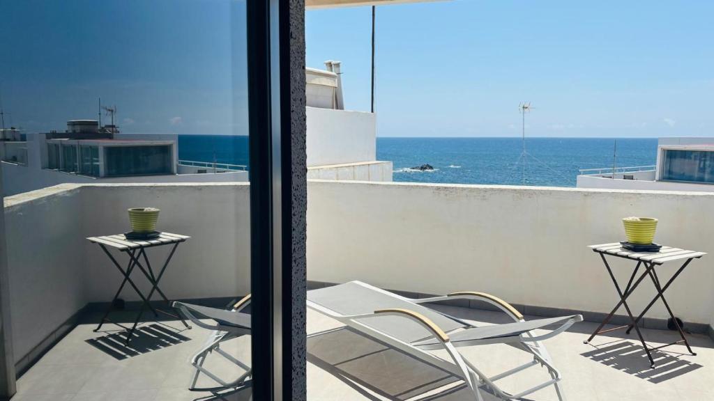 two chairs and tables on a balcony with the ocean at Casa Charlotte El Cotillo in El Cotillo