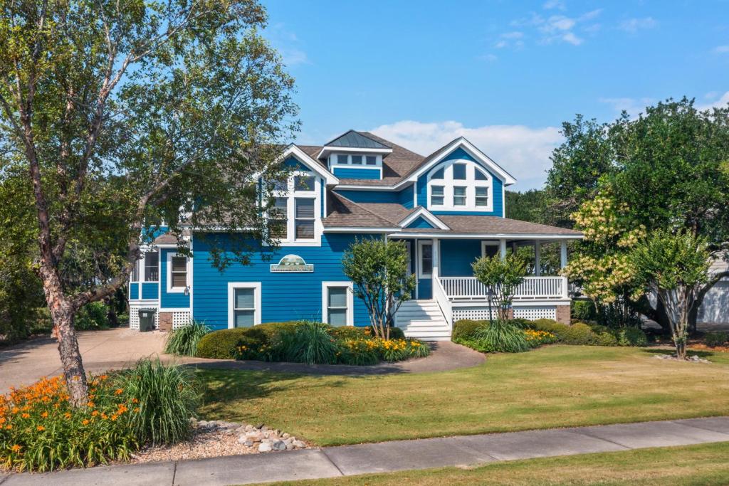 une maison bleue avec des fleurs devant elle dans l'établissement Heaven On Seven, à Corolla