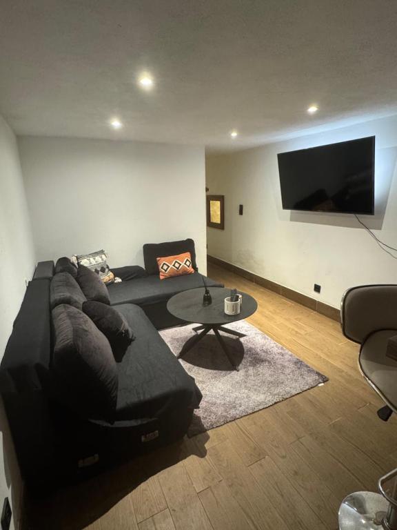 un salon avec un canapé noir et une table dans l'établissement T2 cosy à Sainte-Maxime - Confort & Tranquillité, à Sainte-Maxime
