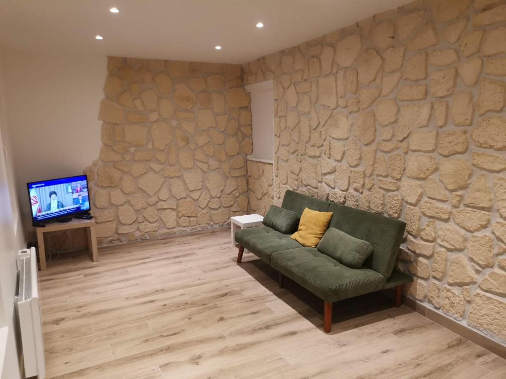 - un salon avec un canapé vert et un mur en pierre dans l'établissement Charmante maison atypique ambiance ville village, à Deuil-la-Barre