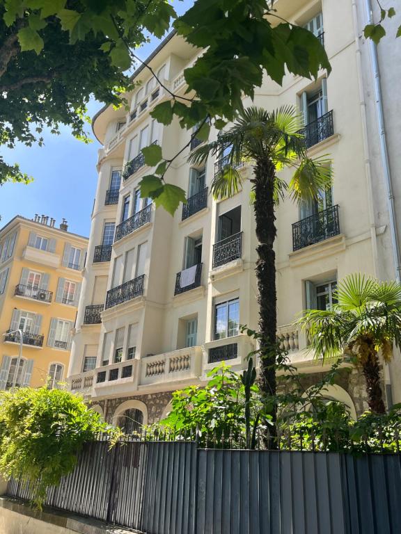 een hoog wit gebouw met een palmboom ervoor bij Studio Carabacel in Nice