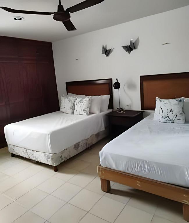 two beds in a room with white walls at Departamento KAY a orilla del Mar, Progreso in Progreso