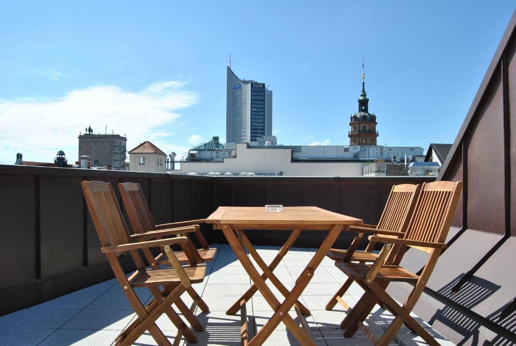 a wooden table and four chairs on a balcony at Trafford Sky Homes in Leipzig