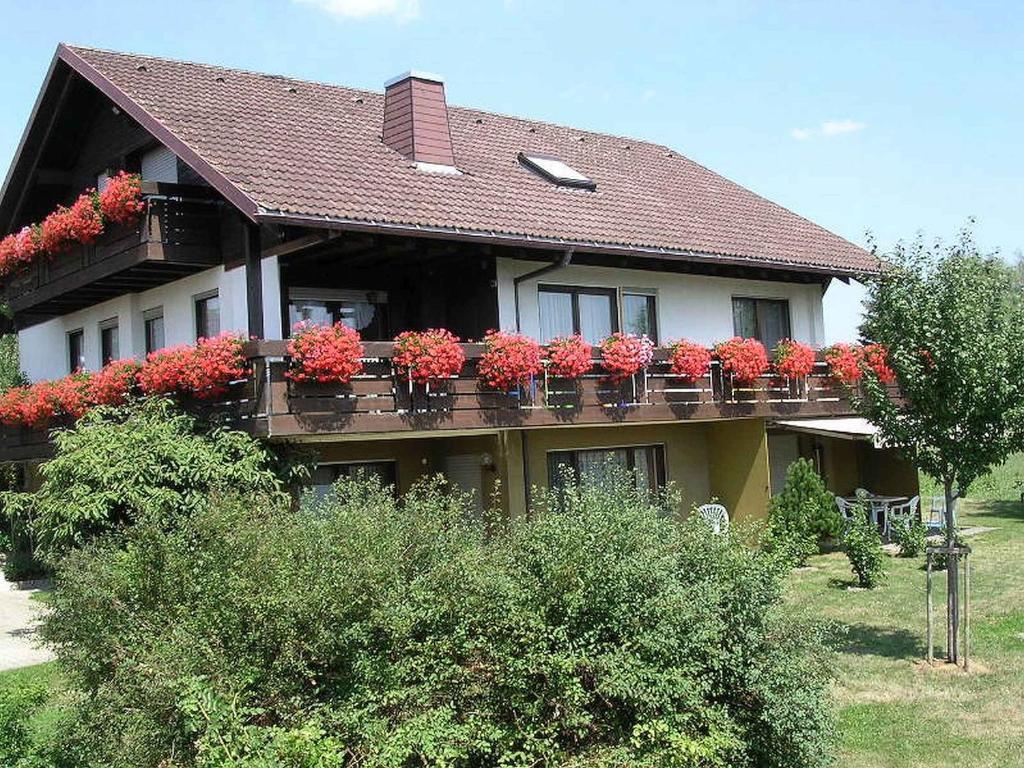 ein Haus mit roten Blumen auf dem Balkon in der Unterkunft Ferienwohnungen Tröndle im Rosendorf in Weilheim