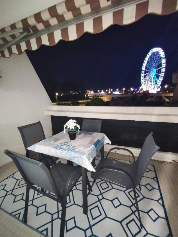 une table et des chaises avec une roue ferris en arrière-plan dans l'établissement Paisible P1 face à la mer a 2 mn de la plage et du Centre Ville, à La Grande Motte