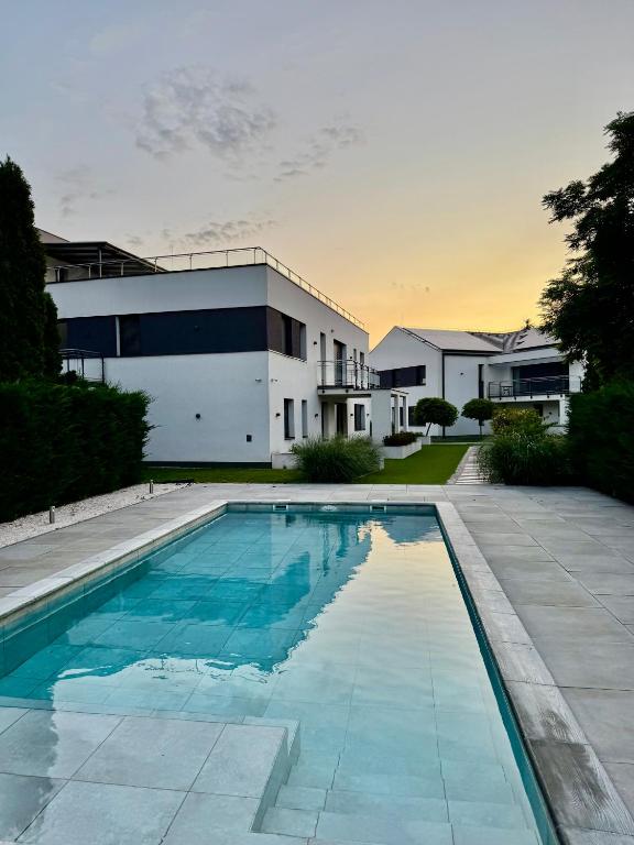 a swimming pool in front of a house at Penthouse Happy Seasons in Hajdúszoboszló