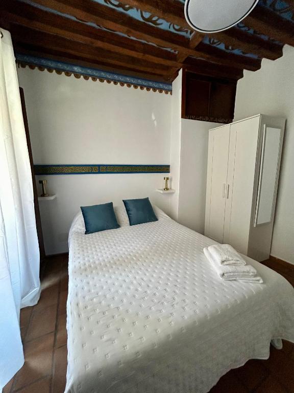 a bedroom with a large white bed with blue pillows at Casa Alba in Alcalá de Henares