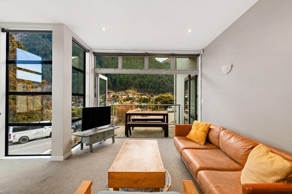 ein Wohnzimmer mit Sofa und Tisch in der Unterkunft At Home on Hallenstein, entire 3 bedroom townhouse in Queenstown