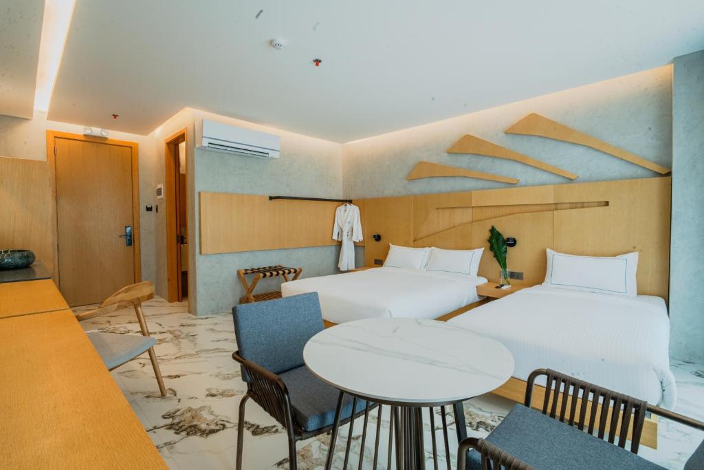 a hotel room with two beds and a table and chairs at The Hotel Elizabeth Resort and Villas - Long Beach San Vicente Palawan in San Vicente