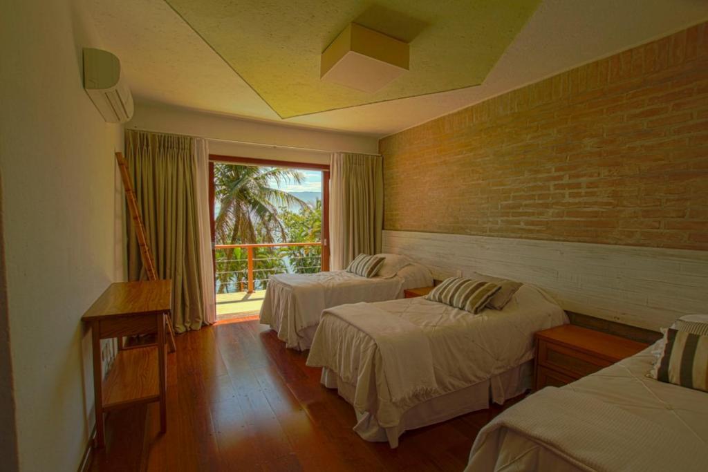 a hotel room with two beds and a window at Villa Bermahe in Ilhabela