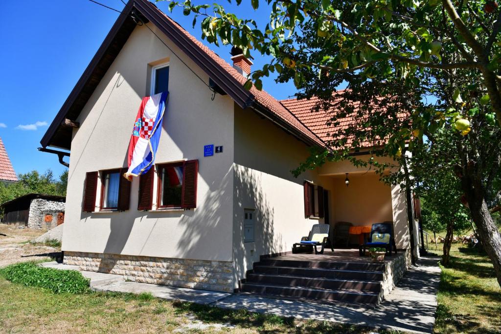 a white house with a flag on it at Holiday house with a parking space Saborsko, Plitvice - 23935 in Saborsko