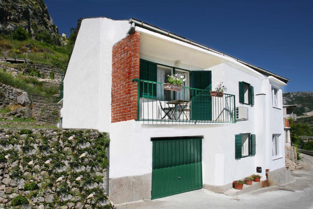 Cette maison blanche dispose d'une porte verte et d'un balcon. dans l'établissement Holiday Home Miklica, à Klis