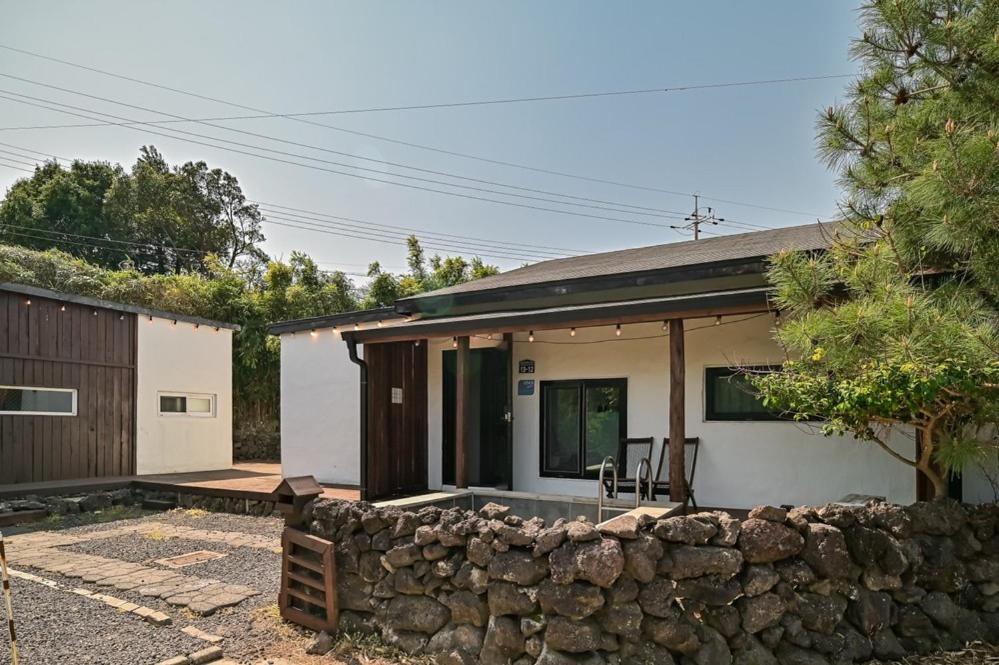 a house with a stone wall in front of it at Jejuya Pyoseon in Seogwipo