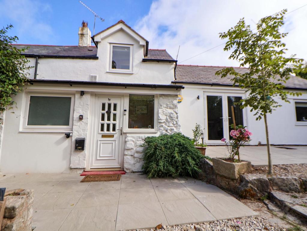 a white house with a white door and a driveway at Cartref in Holywell