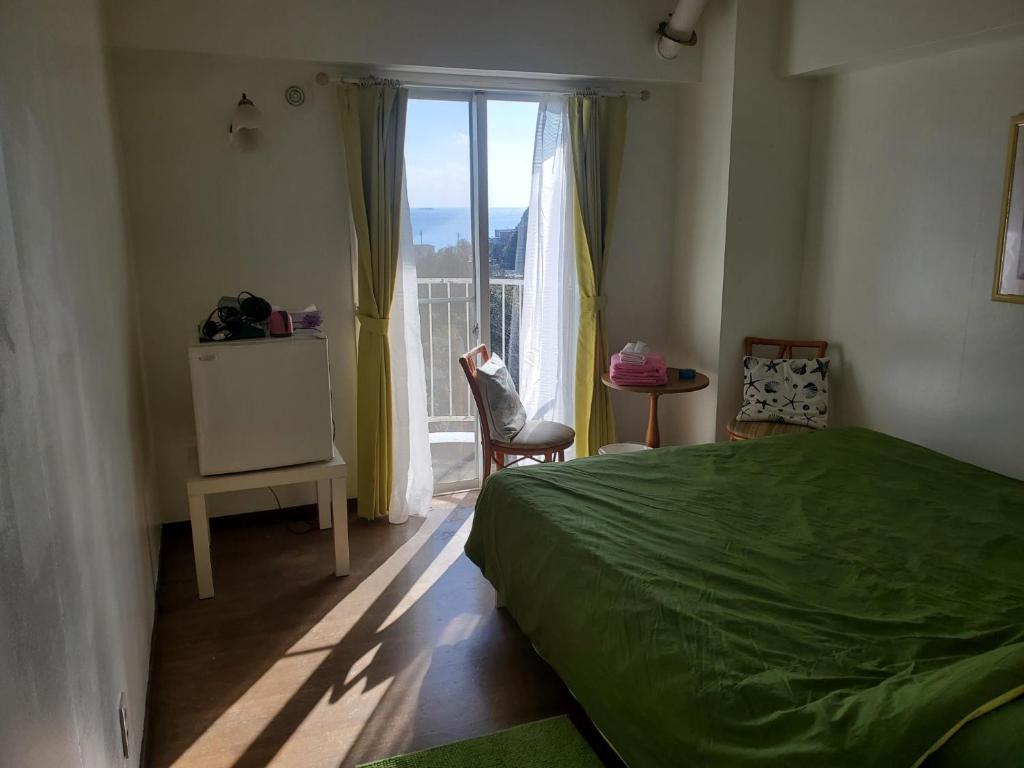 a bedroom with a green bed and a window at ビーチキャッスルマイウェイ in Shimoda