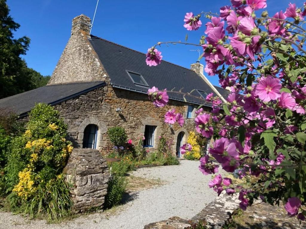 un bâtiment en pierre avec des fleurs devant lui dans l'établissement Charmante Longère Bretonne au Calme, Proche Mer - FR-1-639-135, à Sarzeau