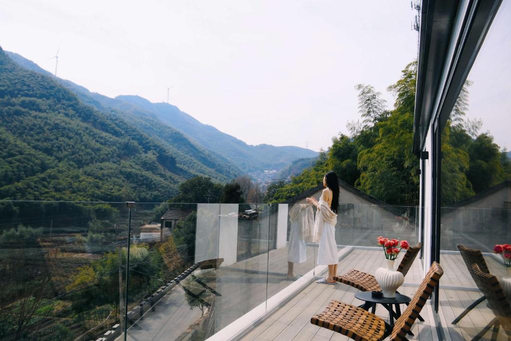 a woman standing on a balcony looking out at the mountains at Wuxing Qinglan Homestay in Houhong