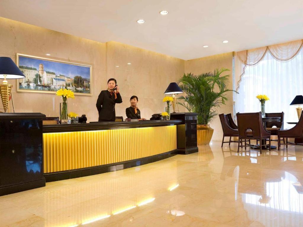 zwei Personen stehen an einer Bar in einer Hotellobby in der Unterkunft Teda Dalian in Dalian