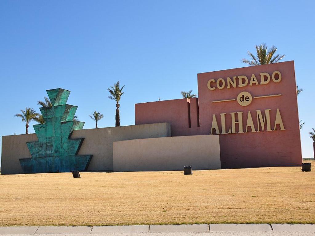 una señal frente a un edificio con palmeras en Condado de Alhama N5, en Alhama de Murcia