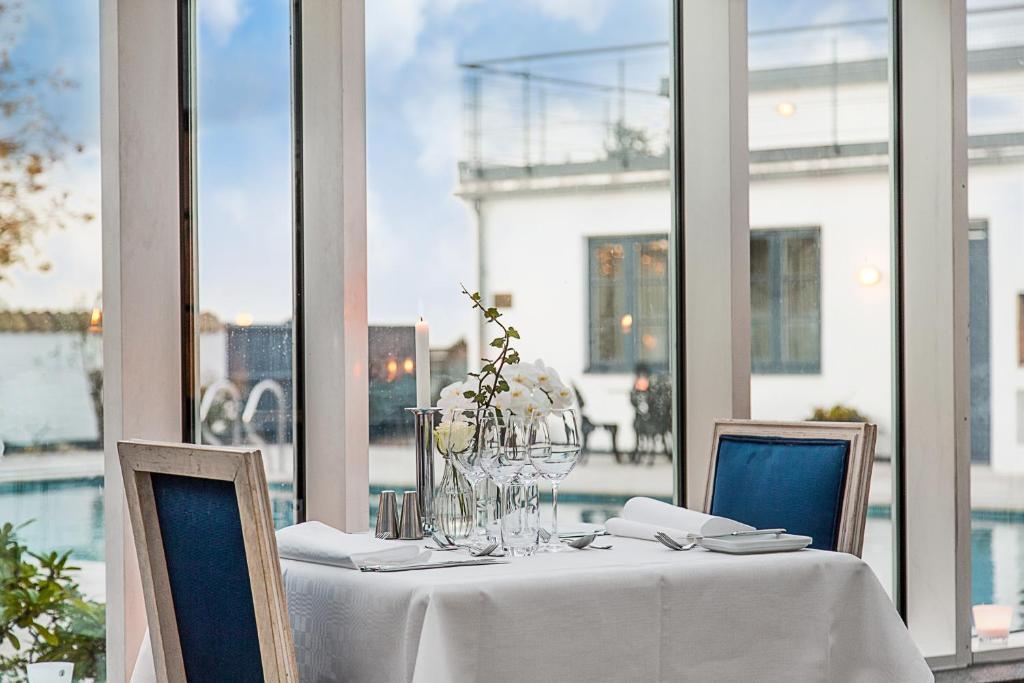 a table with a white table cloth and chairs and windows at Hotell Gässlingen in Skanör med Falsterbo