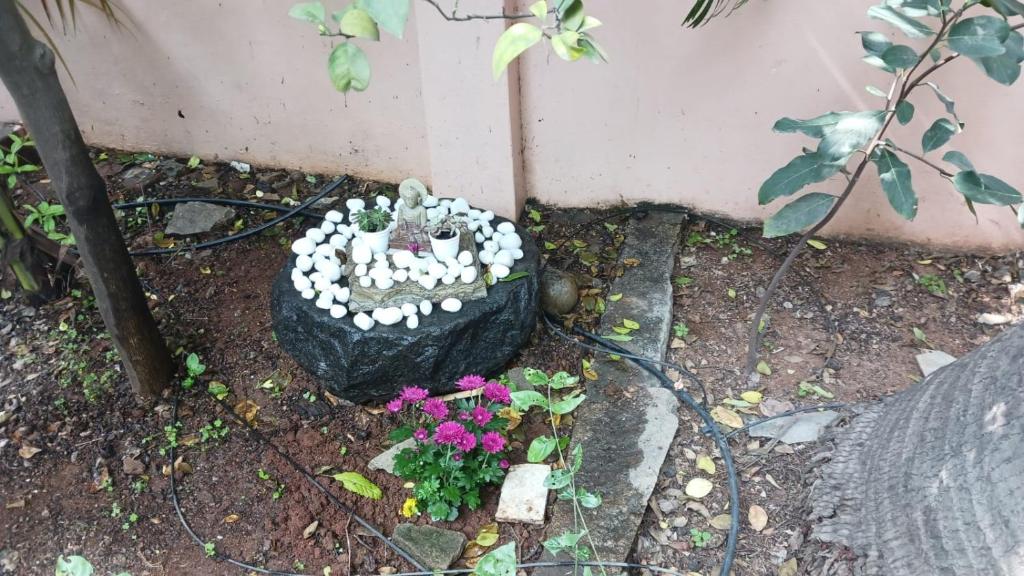 a garden with a statue and flowers in the dirt at Garden Villa, Hyderabad in Hyderabad