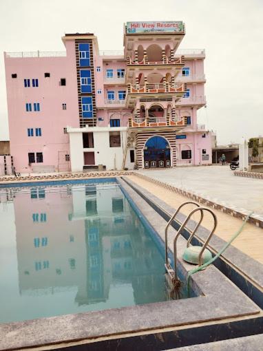 einem Pool vor einem großen Gebäude in der Unterkunft Hill view resort in Jaipur