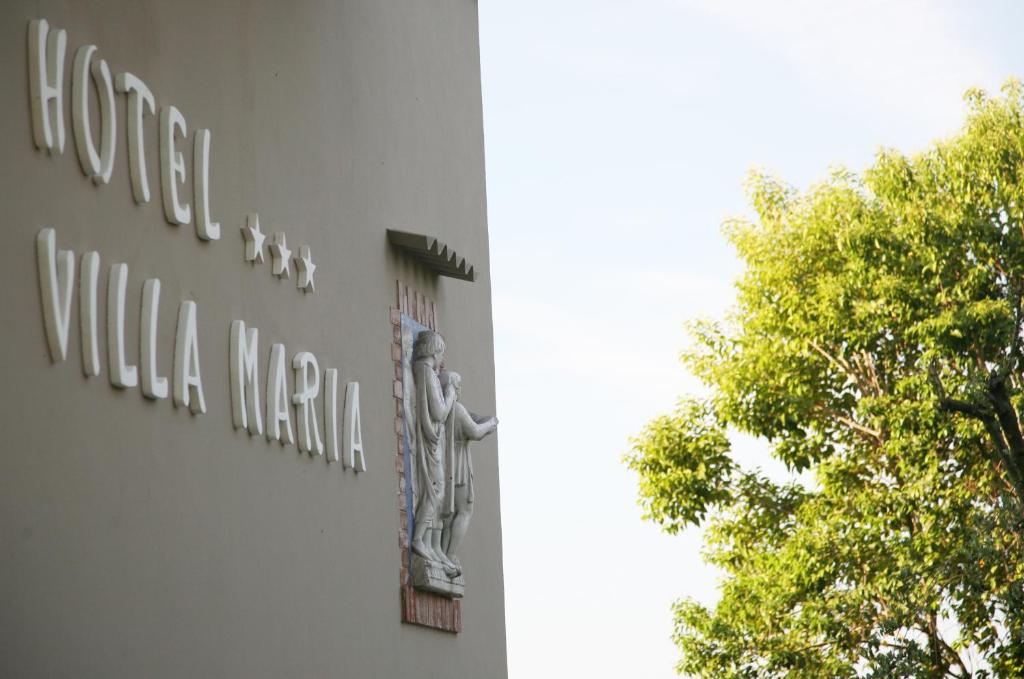 a sign on the side of a building with a tree at Hotel Villa Maria in Sirmione