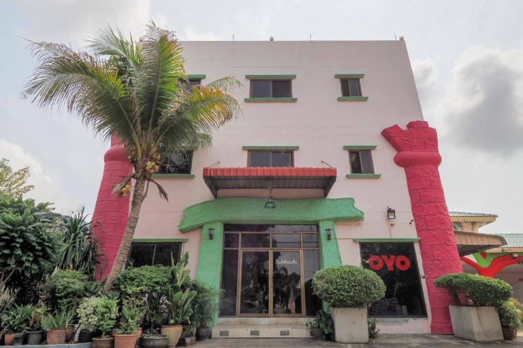 ein Gebäude mit zwei Palmen davor in der Unterkunft OYO 577 For Love Hotel in Ban Khlong Krathum Baen