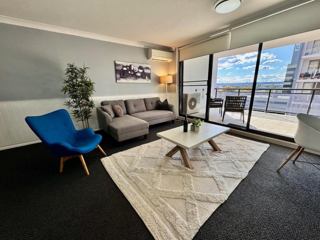 a living room with a couch and a blue chair at Modern 2-Bedroom Apartment 7mins to Paramatta Train Station in Sydney