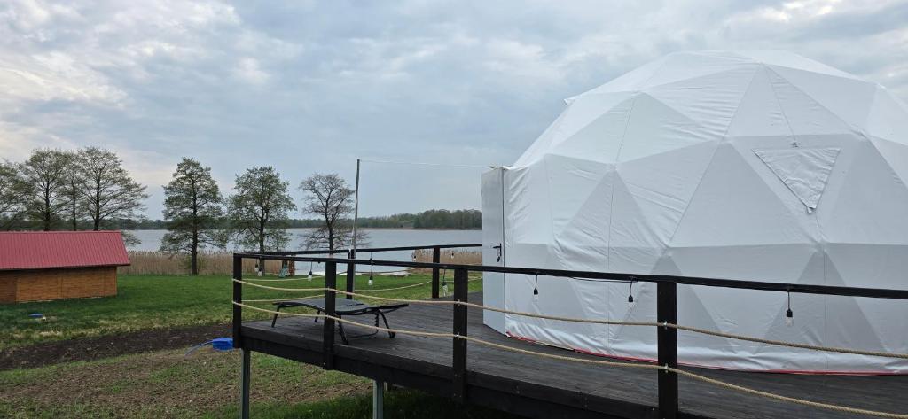 a large white tent sitting on a dock at Domek nad jeziorem Romantyka in Giże