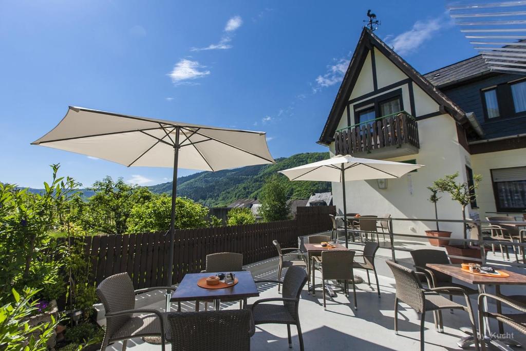 a patio with tables and chairs and an umbrella at Pension Rehschopp in Ediger-Eller