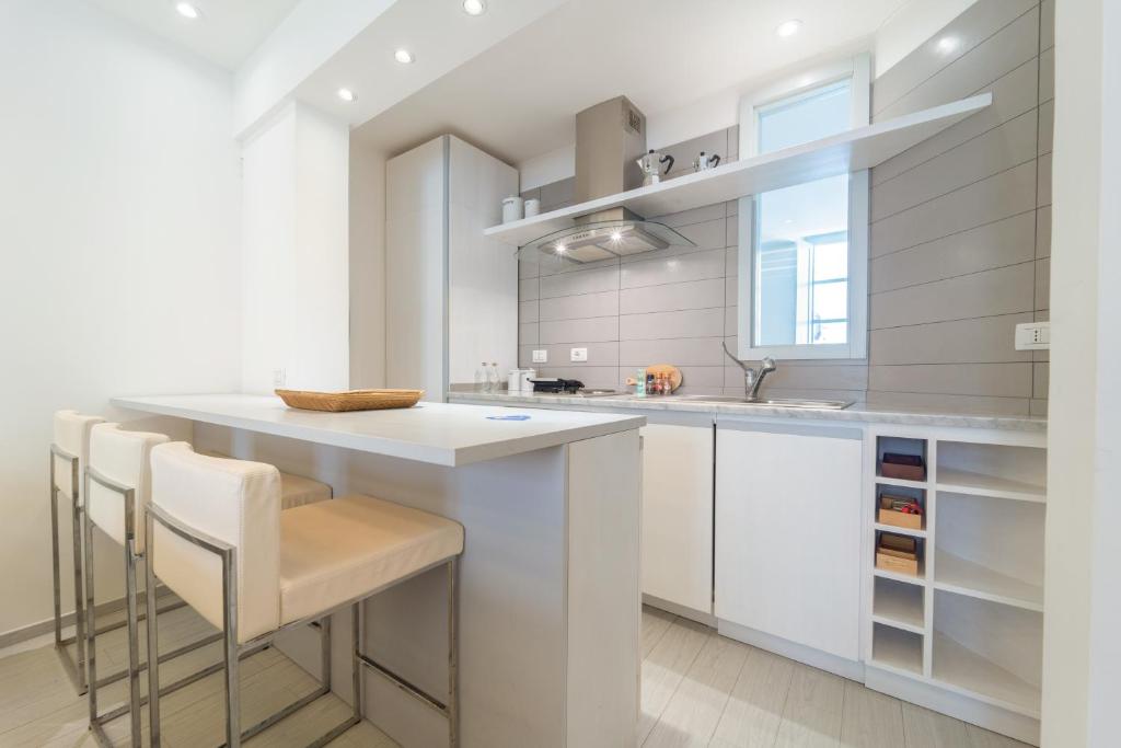 a kitchen with white cabinets and a island with stools at Casa Nova in Alghero