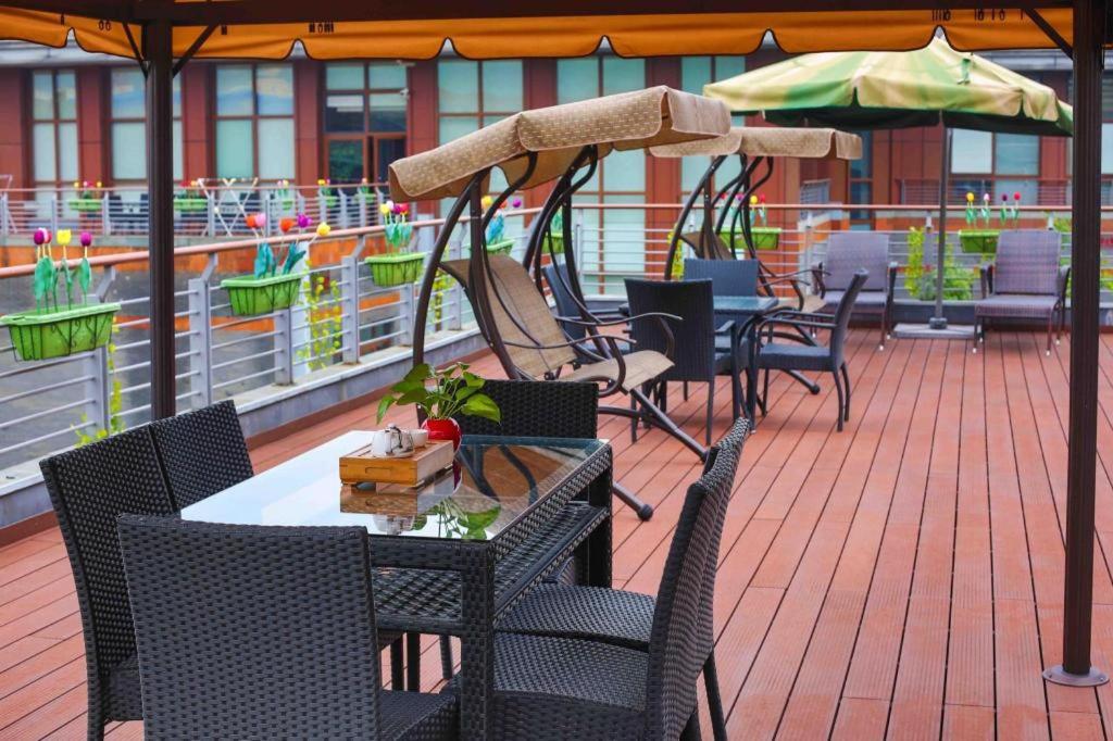 a patio with tables and chairs and an umbrella at Hangzhou Xixi Nade Runzeyuan Hotel in Hangzhou