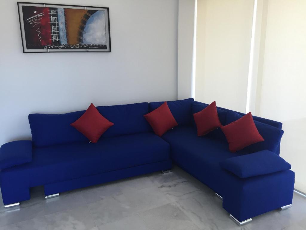 Sofá azul con almohadas rojas en una habitación en Condominios Acqua, Nuevo Vallarta en Nuevo Vallarta 