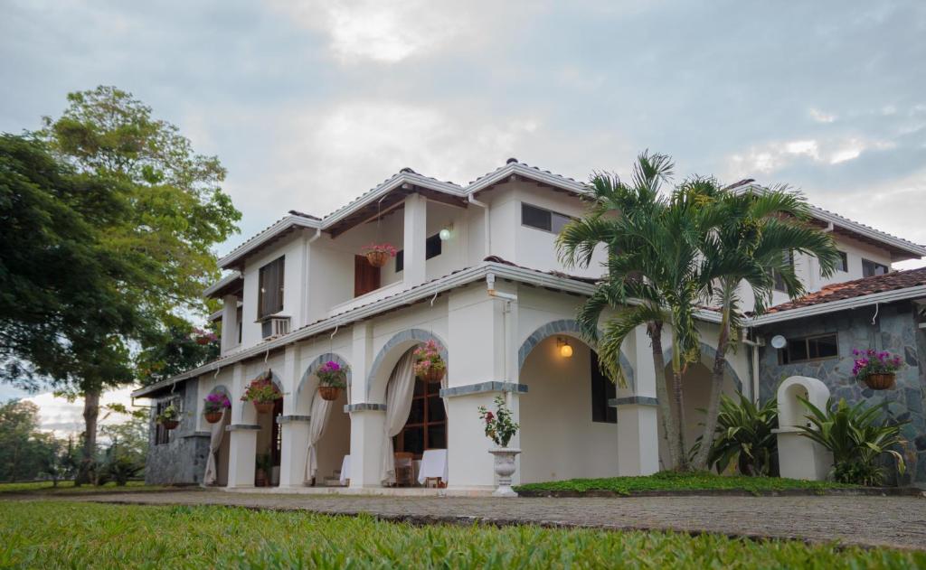 een wit huis met een palmboom bij El Lugar Boutique Hotel in Pereira