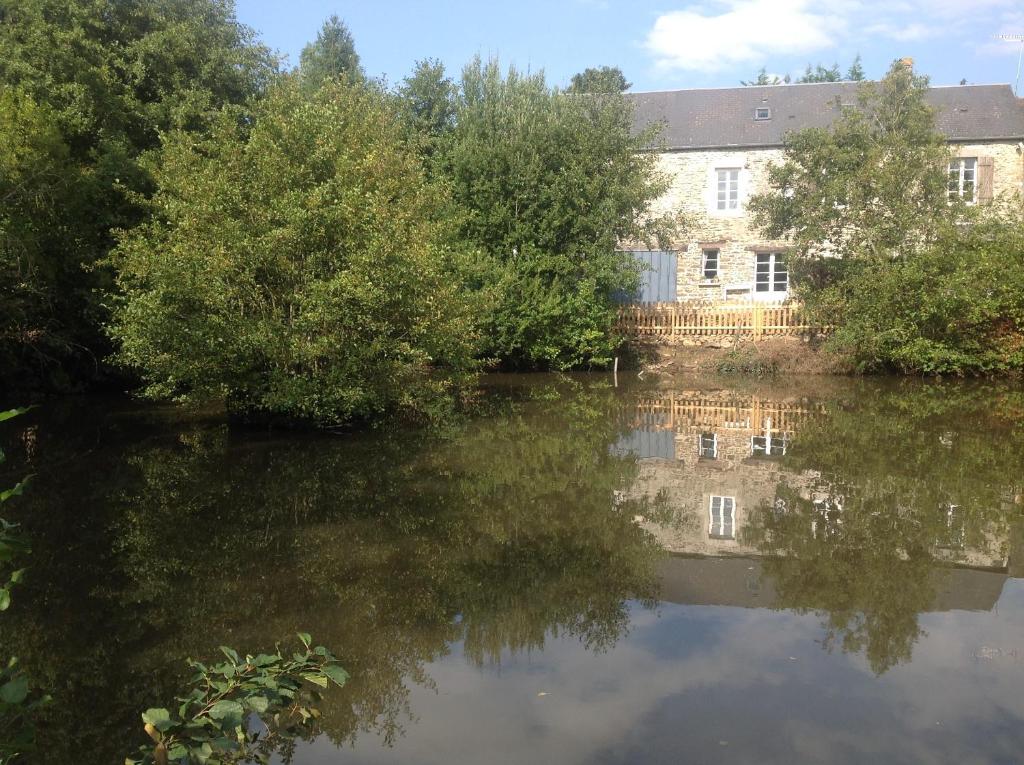 een huis weerspiegeld in het water van een rivier bij L'Ancien Pressoir in Pierrefitte-en-Cinglais