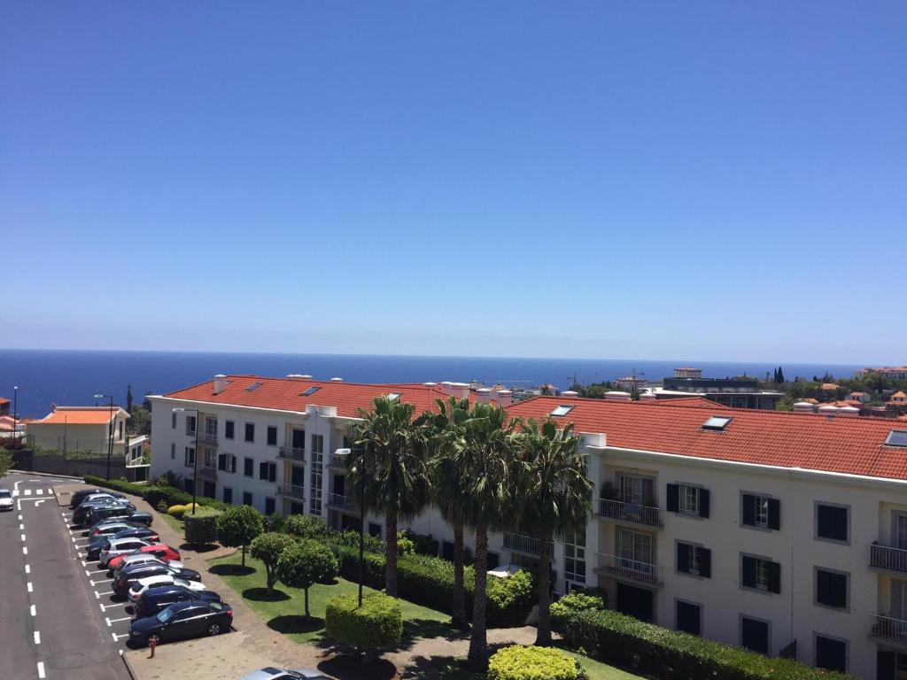 Vista arial de um parque de estacionamento com palmeiras e edifícios em Excelente T3 Duplex Funchal no Funchal