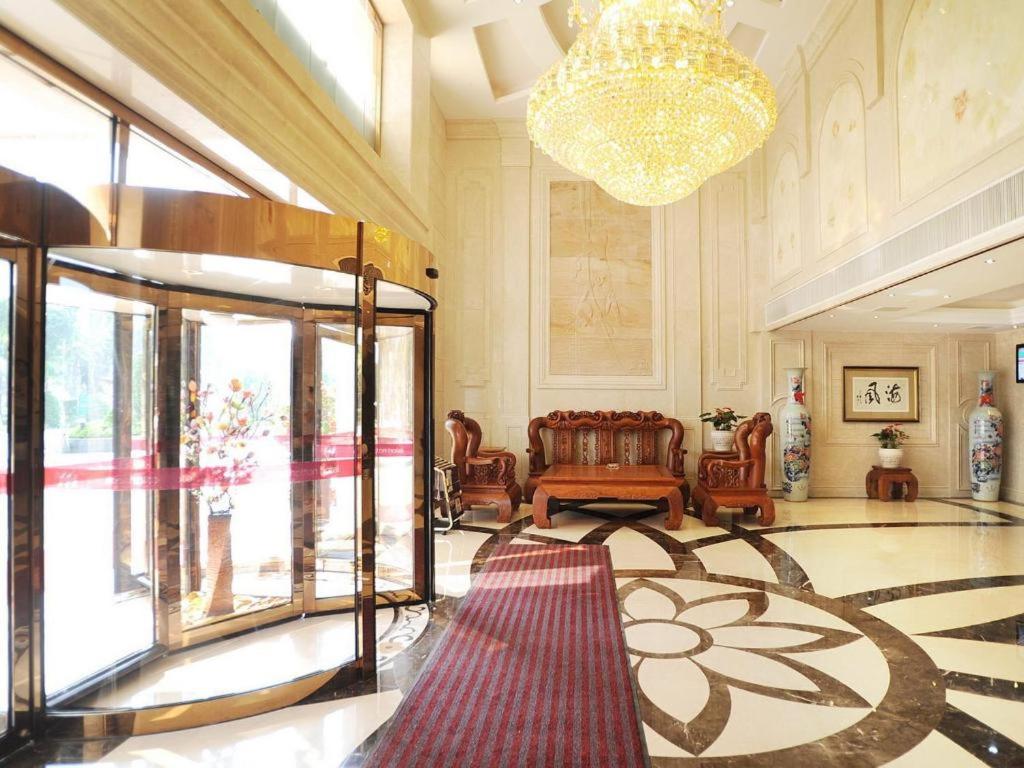 eine Lobby mit einem Kronleuchter und ein Zimmer mit einem Teppich in der Unterkunft Manhatton Hotel Beihai in Dianbailiao