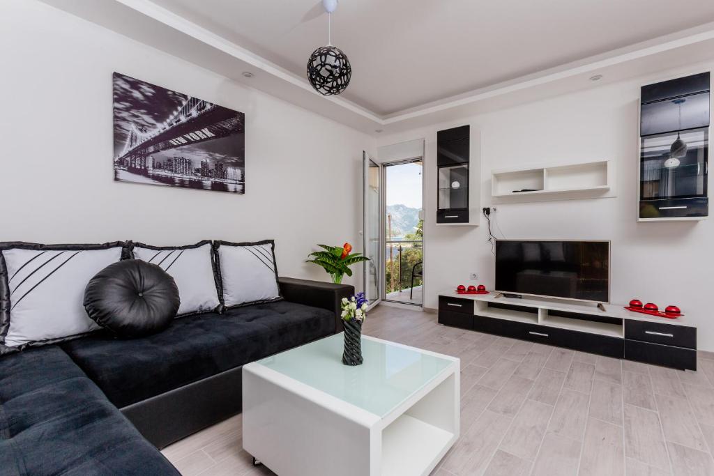 un soggiorno con divano nero e TV di Dream Vacation Apartments a Tivat