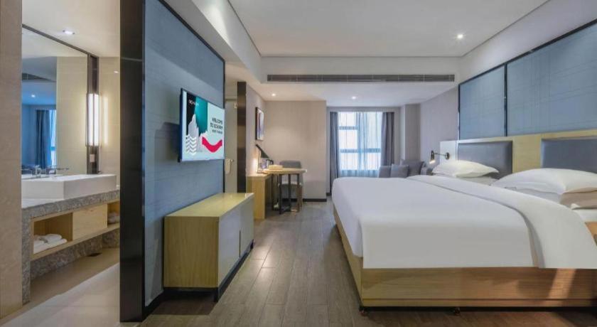 ein großes Schlafzimmer mit einem großen Bett und einem Badezimmer in der Unterkunft Echarm Hotel Beihai Railway Station in Dianbailiao