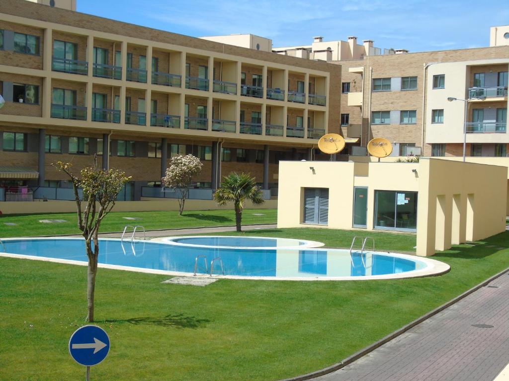 a swimming pool in front of a building at Alojamento Varandas do Parque com INTERNET in Póvoa de Varzim