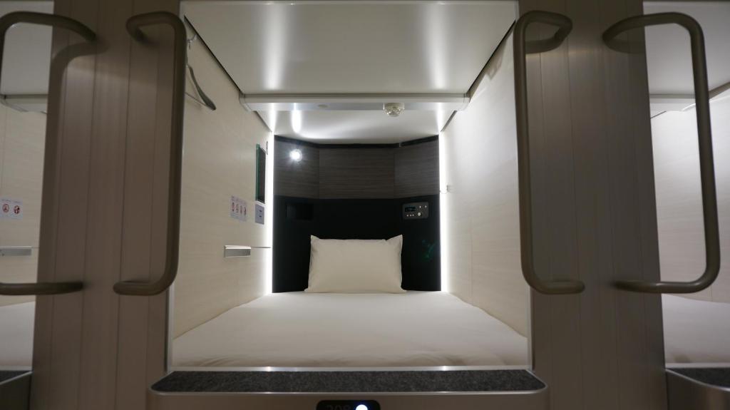 a small room with a bed with a white pillow at Akihabara Bay Hotel (Female Only) in Tokyo