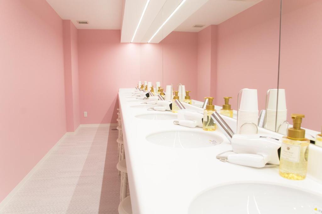 a row of sinks in a bathroom with pink walls at Akihabara Bay Hotel (Female Only) in Tokyo